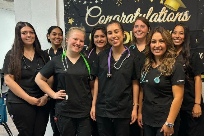 graduates posing with congratulatory sign